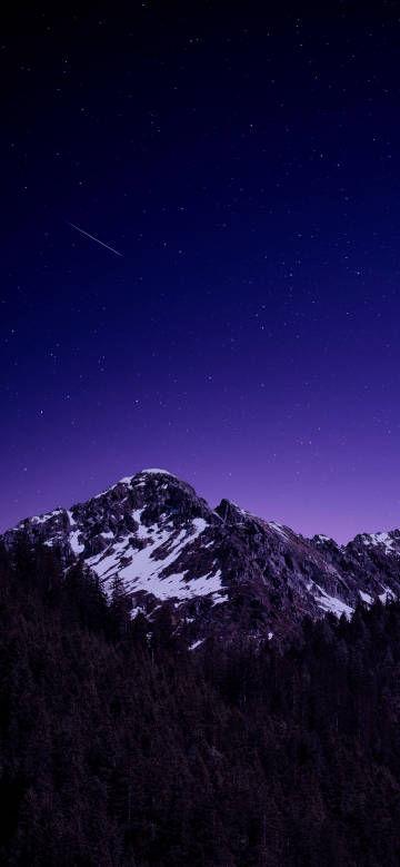 Snowy mountain landscape under a deep purple starry sky
