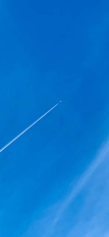 An airplane flying high in a clear blue sky phone wallpaper