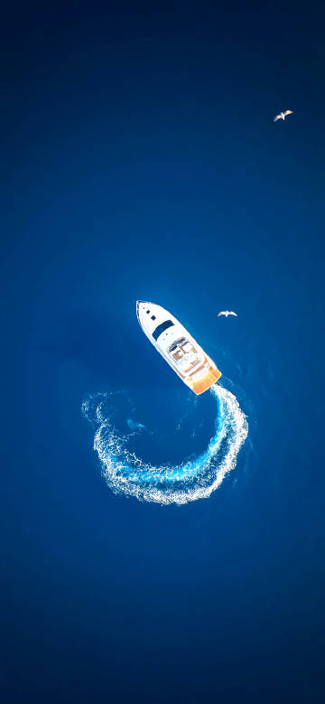 Aerial view of a yacht sailing in the blue sea phone wallpaper