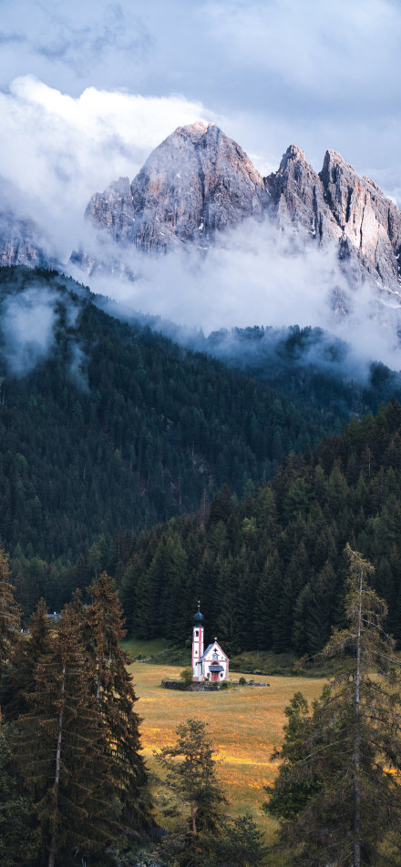 Church surrounded by mountains and forests phone wallpaper