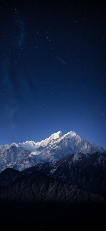 Breathtaking snow-capped mountains under a deep blue starry sky