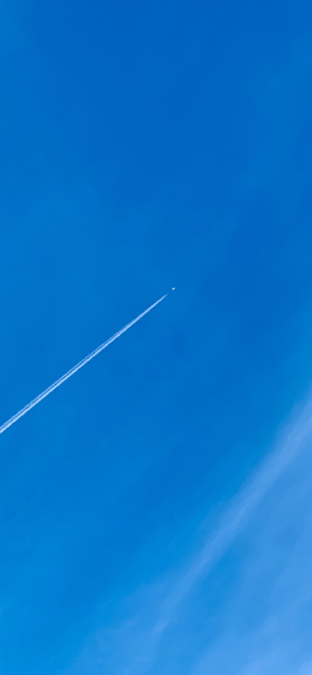An airplane flying high in a clear blue sky phone wallpaper