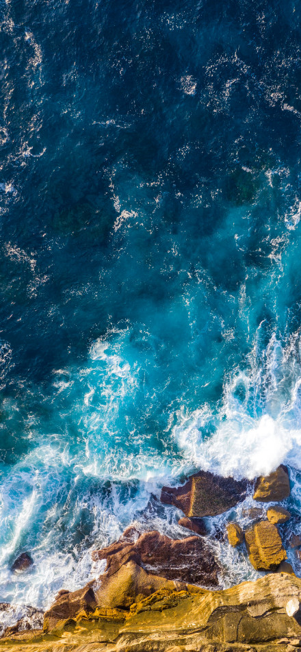 Waves crashing against rocks on seashore phone wallpaper