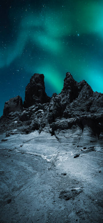 Green aurora dancing in the night sky above the rocks phone wallpaper