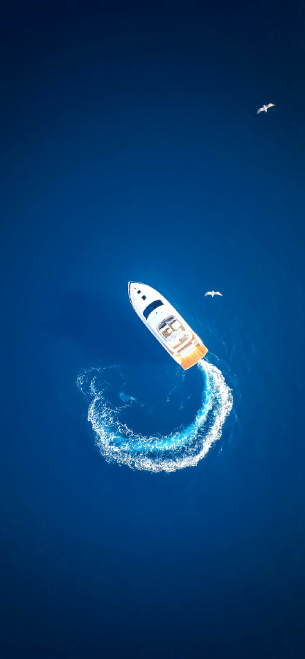 Aerial view of a yacht sailing in the blue sea phone wallpaper