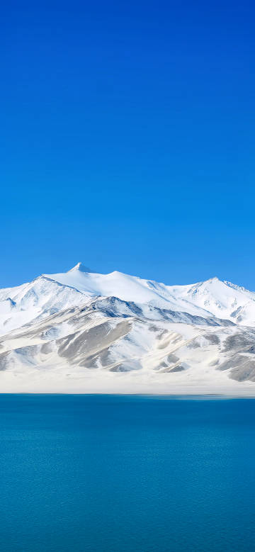 Snow-capped mountains and blue lake under the blue sky