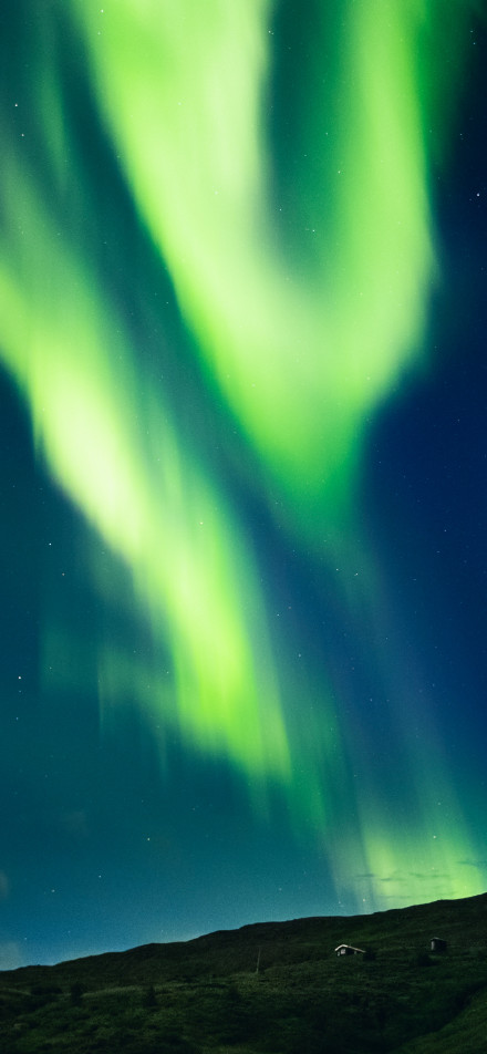 Northern lights illuminating cold hills phone wallpaper