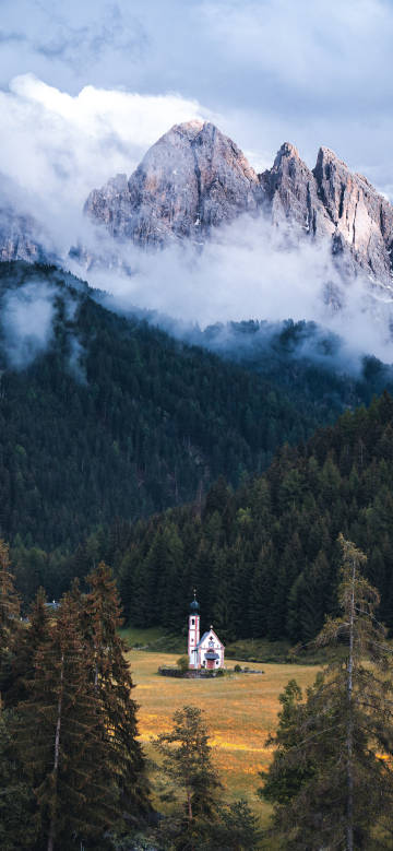Church surrounded by mountains and forests phone wallpaper