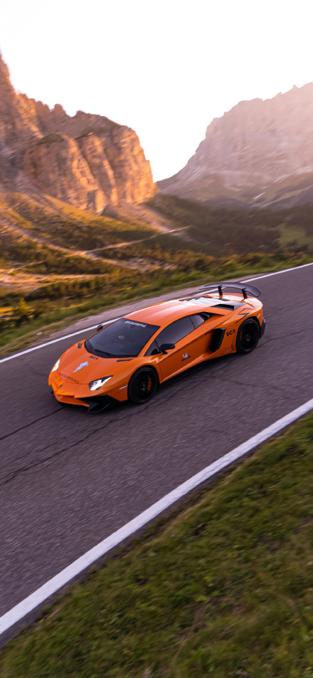 Orange Lamborghini sports car speeding down a mountain highway
