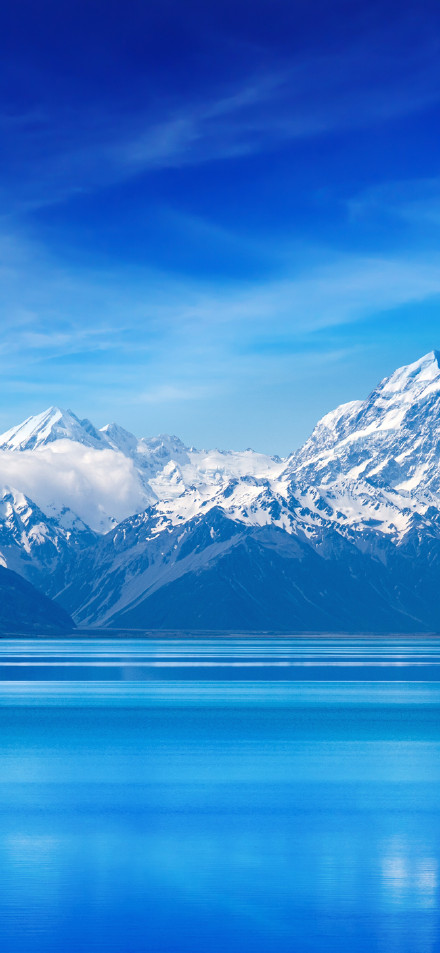 Lofty snow-capped mountains reflecting in blue lake phone wallpaper