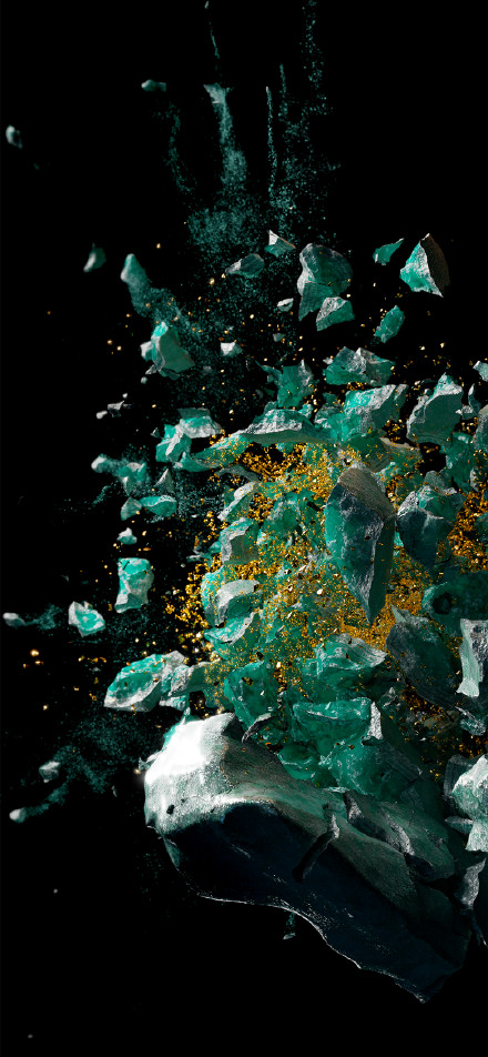 Moment of shattering of emerald green crystal against black background