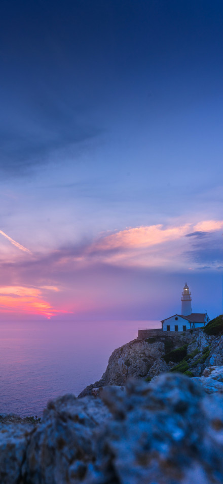 Lighthouse on the cliff by the sea at sunset phone wallpaper