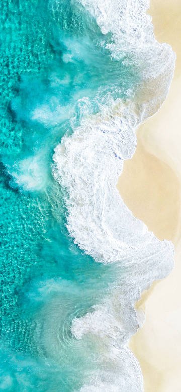 Clear blue-green waters lapping against the golden sandy beach