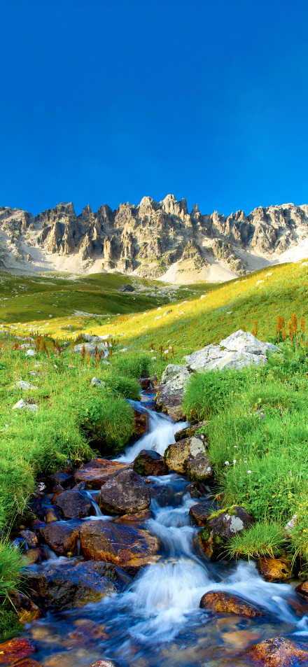 Mountain stream under the rugged mountains wallpaper