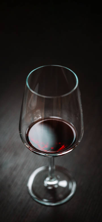 Elegant glass of wine on a dark background IOS26 wallpaper
