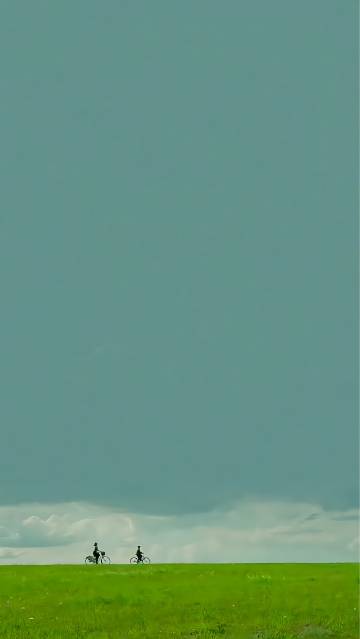 Two Cyclists Under a Minimalist Sky 4K Wallpaper