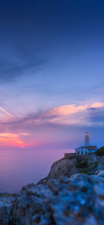 Lighthouse on the cliff by the sea at sunset phone wallpaper