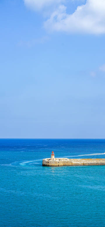 Quiet scene of lighthouse in blue sea phone wallpaper