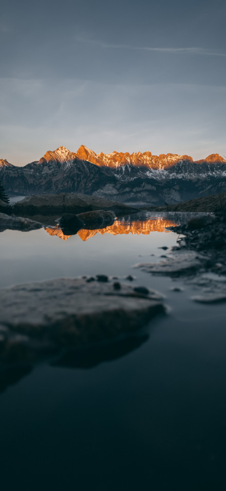 Golden Snowy Mountains Reflecting In A Puddle 8K Wallpaper