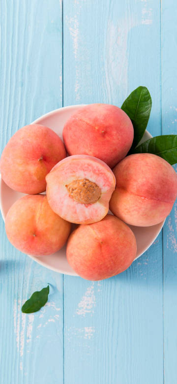 Fresh Pink Peaches On Blue Wooden Table 4K Phone Wallpaper