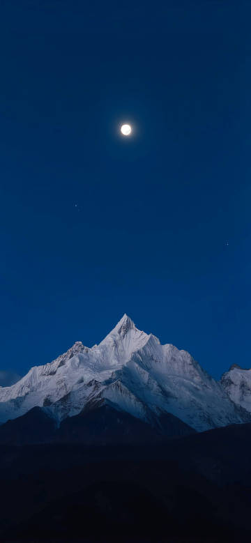 A beautiful view of snowy mountains on a moonlit night