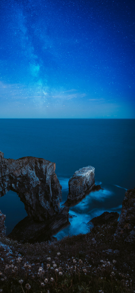 Coastal wonder under starry sea phone wallpaper