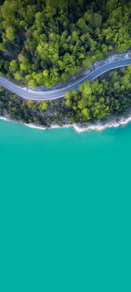 Scenery of highway amidst green forest and blue water