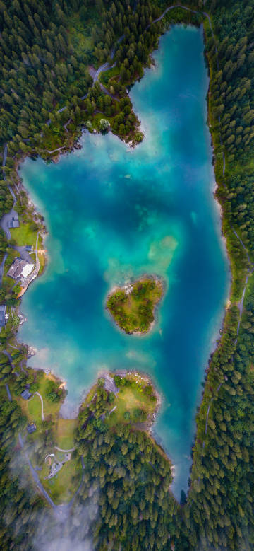 Aerial photo of a blue-green lake surrounded by dense forests