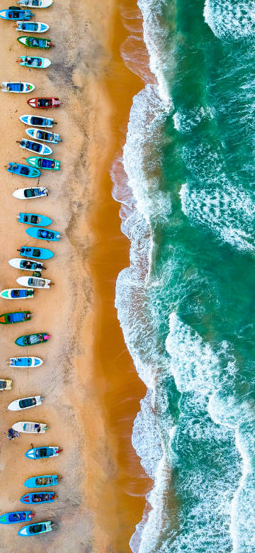 Overlooking the colorful boats lined up on the beach phone wallpaper