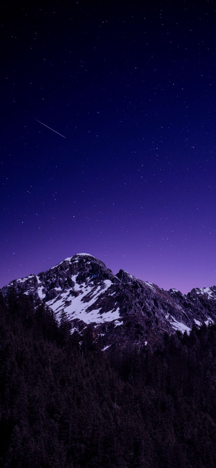 Snowy mountain landscape under a deep purple starry sky