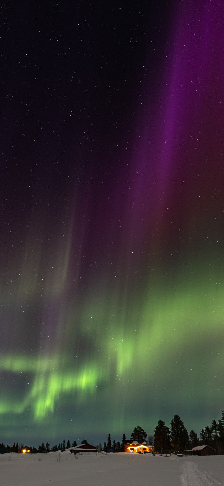 Green And Purple Aurora Over A Snowy Village 4K Wallpaper