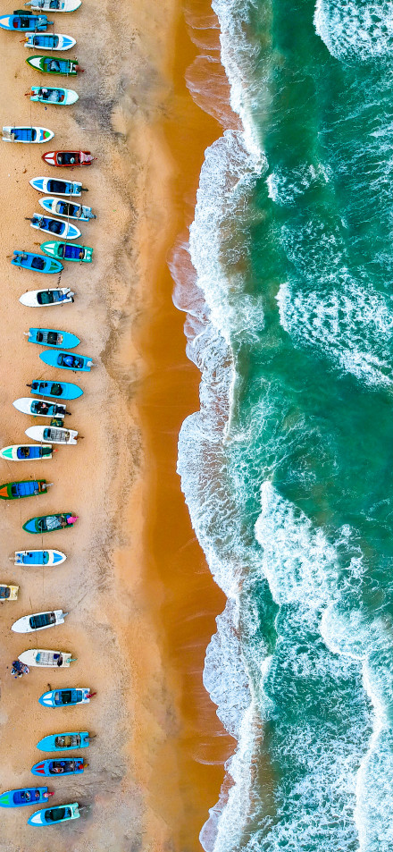 Overlooking the colorful boats lined up on the beach phone wallpaper