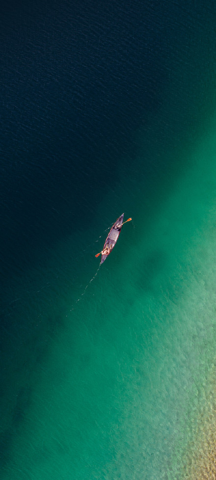 Overlooking a leisurely boat on the emerald green lake phone wallpaper
