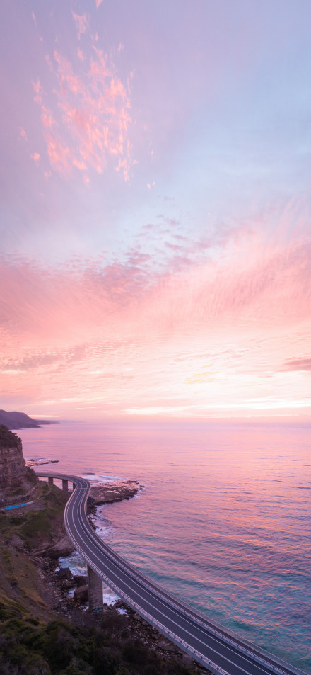 Coastal highway in pink-purple afterglow phone wallpaper