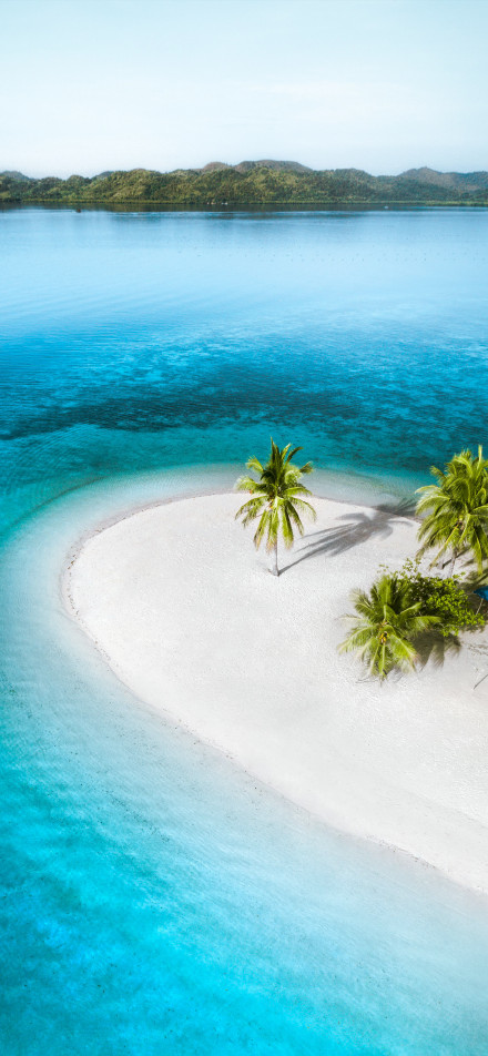 Tropical island surrounded by clear blue-green water phone wallpaper