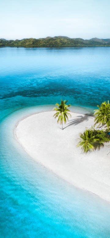 Tropical island surrounded by clear blue-green water phone wallpaper