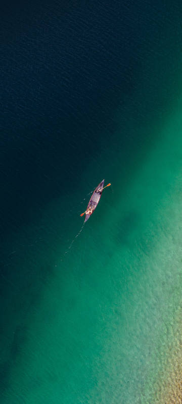 Overlooking a leisurely boat on the emerald green lake phone wallpaper